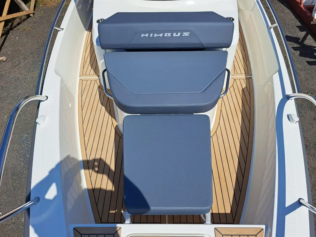 A top view of a boat interior featuring blue cushions labeled 'NIMBUS' and wooden flooring, showcasing a sleek design.
